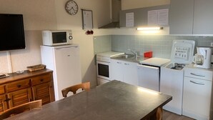 Een functionele keuken met een magnetron, oven, spoelbak en koffiezetapparaat.