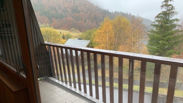 Een balkon met uitzicht op een bebost gebied en een weg.