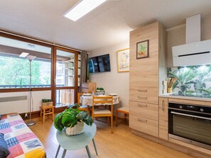 A compact living space with a kitchenette, a dining area, and a large window providing natural light. - Studio 4 ppl Saint Lary Village near cable car (Saint-Lary-Soulan)