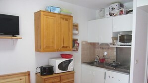 A compact kitchen with wooden cabinets, a microwave, a toaster, and a small dining table. - Studio for 4 at Contamines with terrace and parking (Les Contamines-Montjoie)