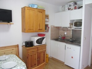 A compact kitchen with wooden cabinets, a microwave, a toaster, and a small dining table. - Studio for 4 at Contamines with terrace and parking (Les Contamines-Montjoie)