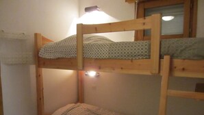 A bunk bed with a wooden frame, a pillow with a geometric pattern, and a small wooden stool with a cat figurine. - Studio for 4 at Contamines with terrace and parking (Les Contamines-Montjoie)