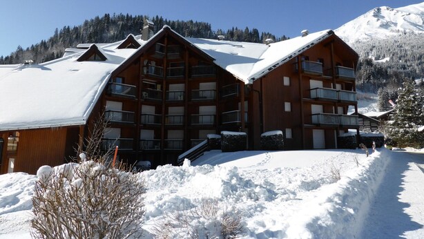 A multi-story wooden lodge with balconies, surrounded by snow-covered mountains. - Studio for 4 at Contamines with terrace and parking (Les Contamines-Montjoie)