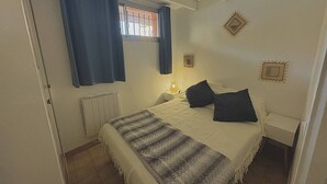 A bedroom with a bed, a nightstand, a window with curtains, and decorative wall art.
