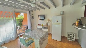 A compact kitchen with a refrigerator, a dining table, and a TV.