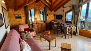 Un interno accogliente in legno con divano, tavolo da pranzo e angolo cottura.