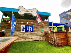 Ein rustikaler Außenbereich mit Holzverkleidung, einem Schild mit der Aufschrift "the Dog Bar" und Wimpeln.