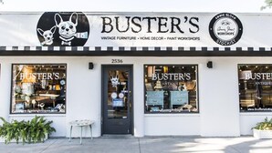 Een winkelgevel met de naam 'Buster's' en een bord waarop staat dat er vintage meubels, woondecoratie en verfworkshops worden aangeboden.