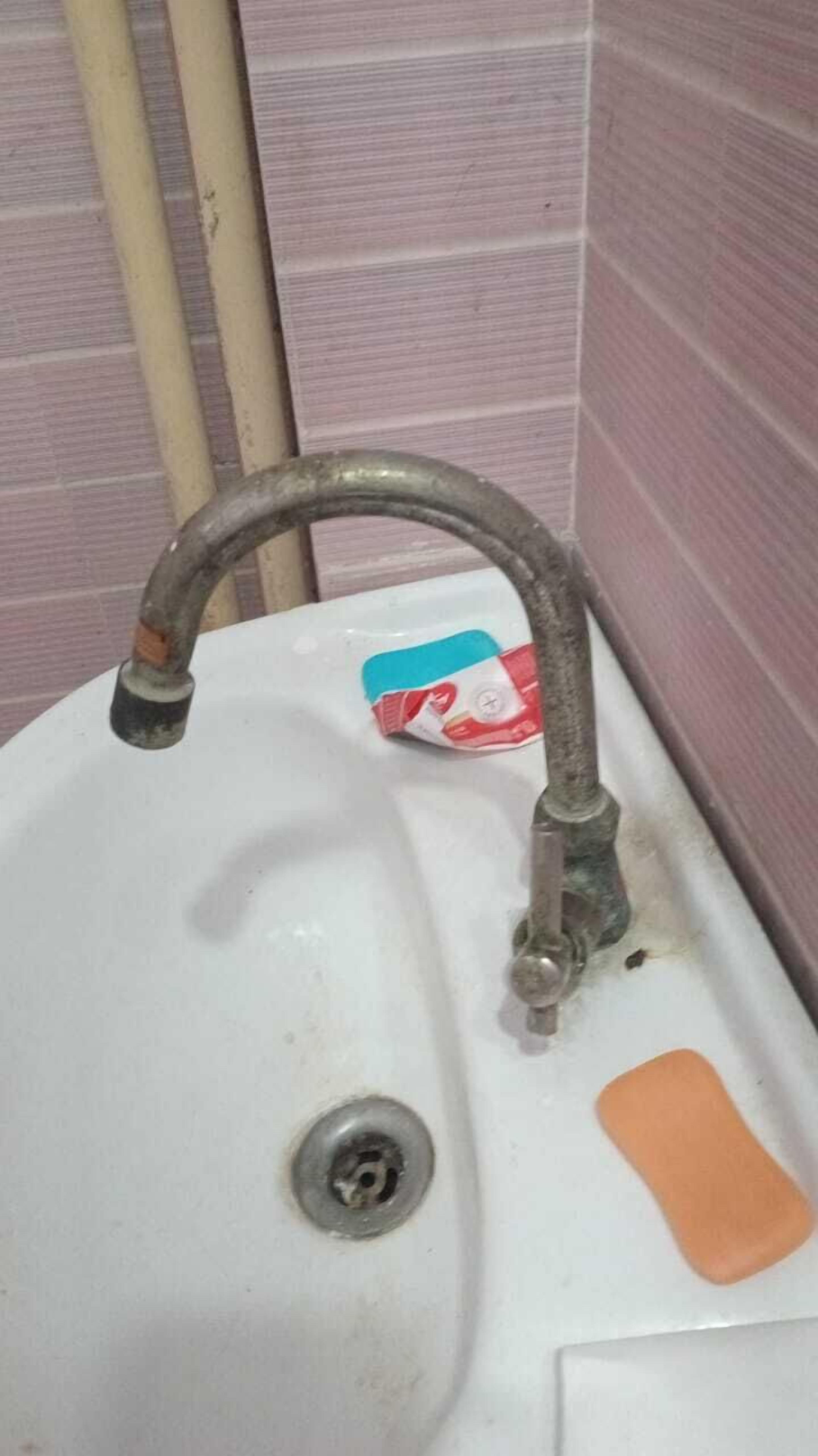 Een wastafel met een enkele kraan, een zeepdispenser en een afvoer.