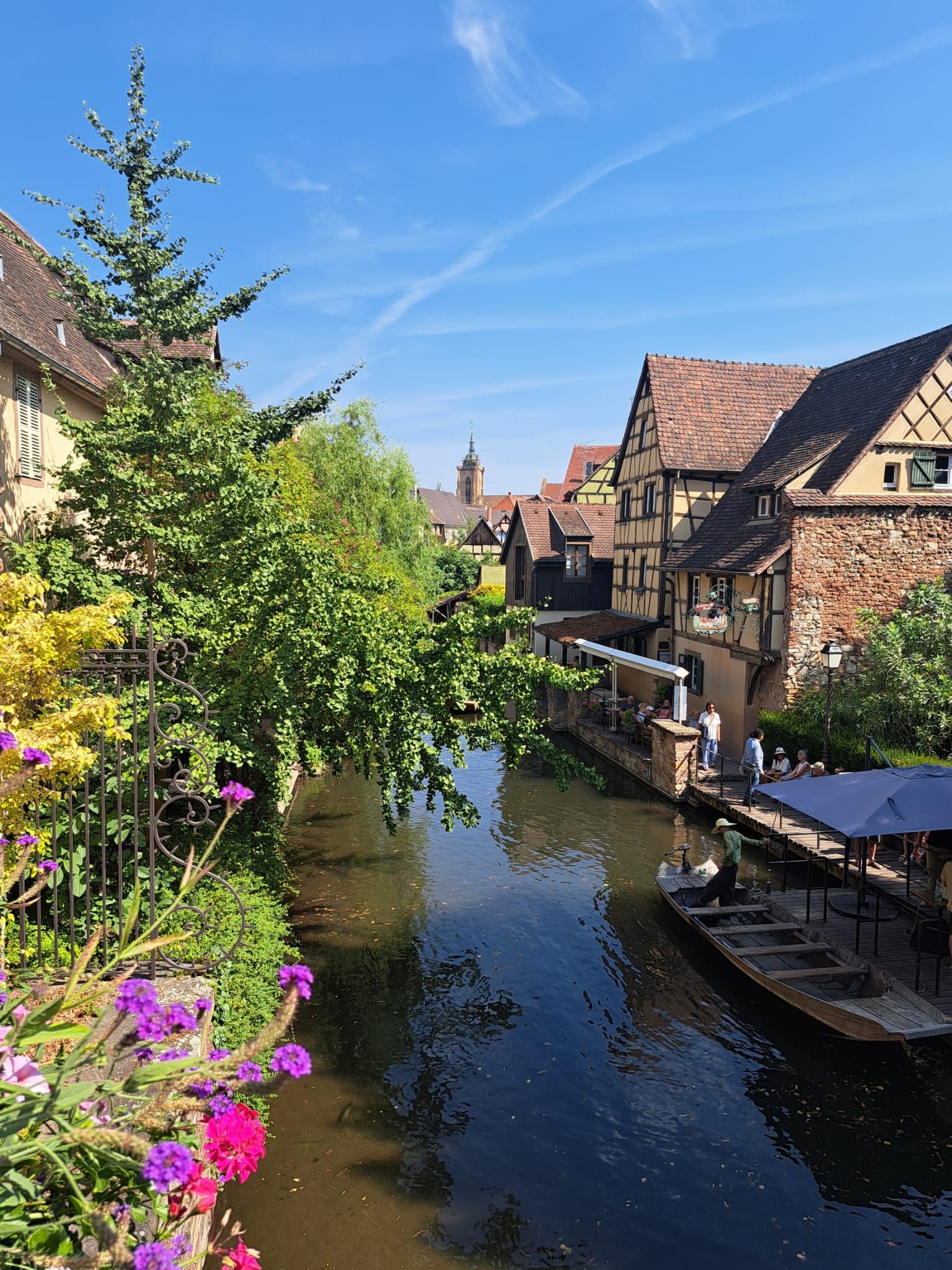 Ein Kanal mit traditionellen Gebäuden an einer Seite und einem Kirchturm in der Ferne.