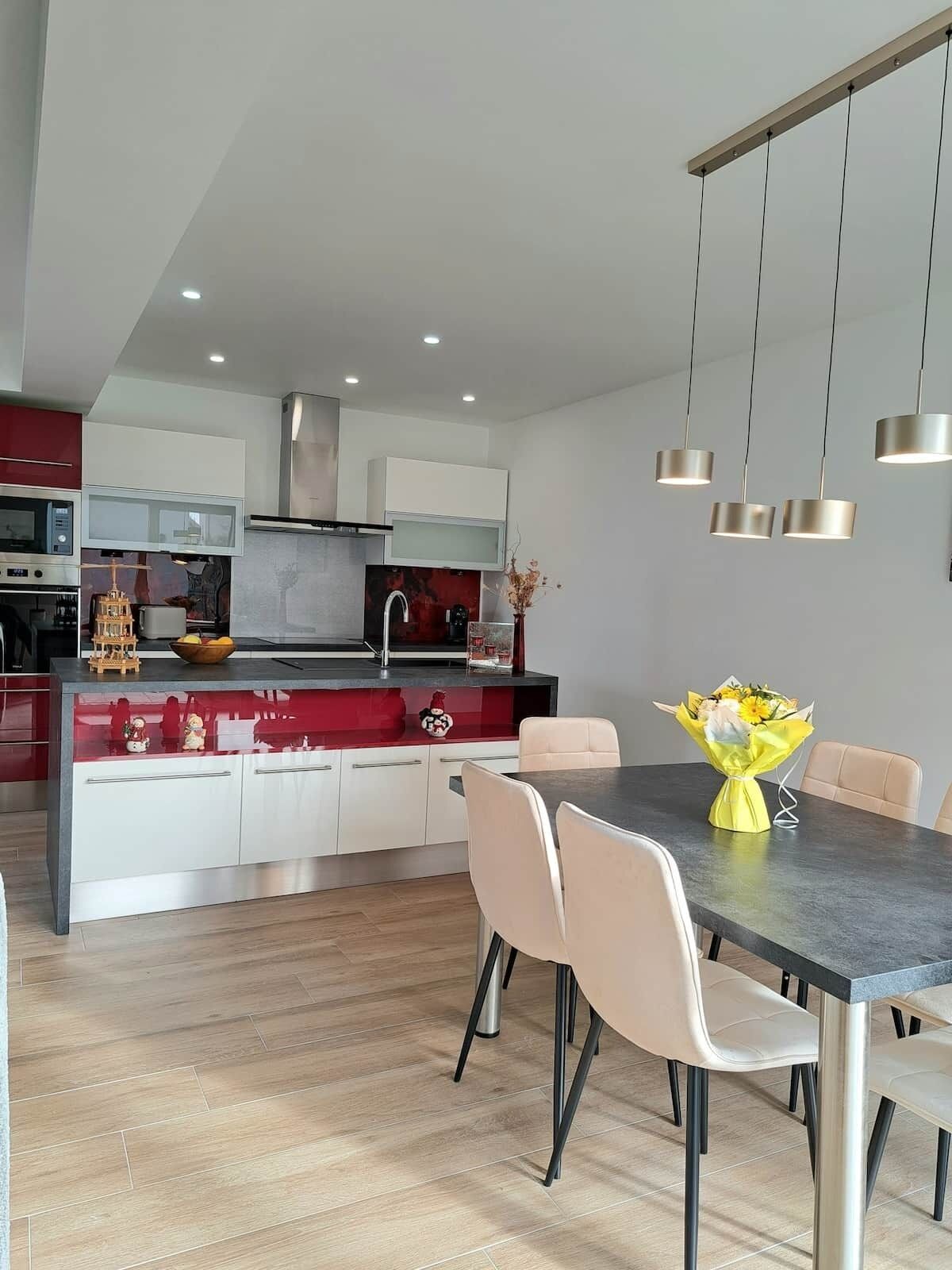 A modern kitchen with a central island, white cabinetry, and a dining area with a table and chairs.