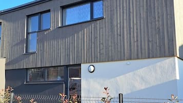 Een modern gebouw met twee verdiepingen, een plat dak, grote ramen en een zichtbare garage-ingang.