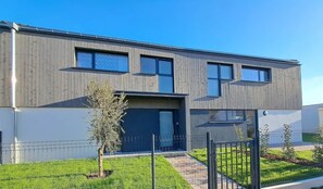 A modern two-story building with a flat roof, large windows, and a visible garage door. - Chez Fernand - New home in Colmar with parking and a garden (Colmar)