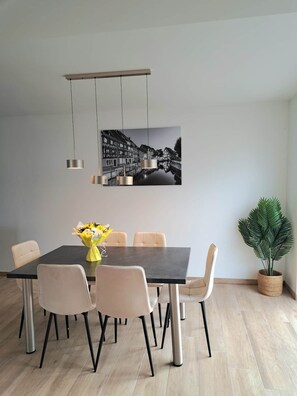 Un comedor con una mesa, sillas, una lámpara colgante y un cuadro en la pared.