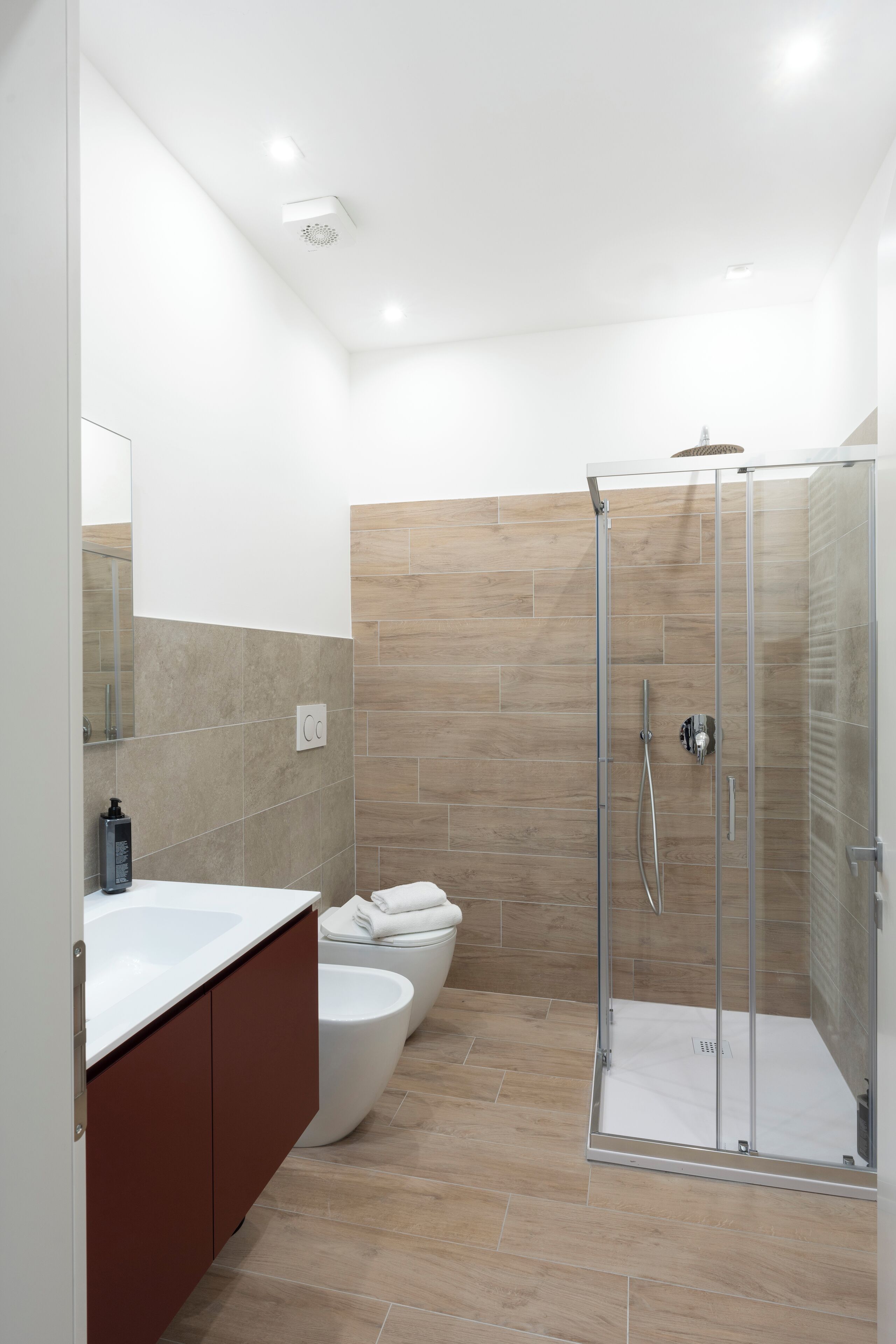 A modern bathroom with a glass-enclosed shower, a white sink, and a toilet.