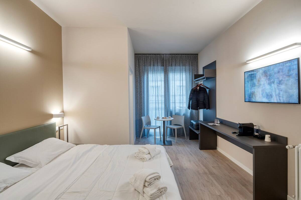 Une chambre d’hôtel comprenant un lit, un bureau avec une chaise, une télévision et un porte-manteau.