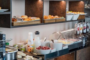 Un buffet con diversi cibi, tra cui pasticceria, frutta e un angolo dedicato alle bevande.