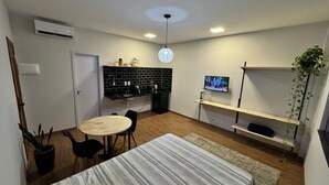 A compact living space with a kitchenette, a dining area, a TV mounted on the wall, and a plant. - Stylish Loft in Salvador's Historic Center – Walk to Pelourinho (Salvador)
