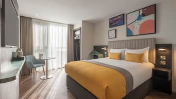 A hotel room with a bed, bedside tables, a desk, and a chair.