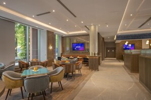 A modern interior with a bar area, seating, and a TV screen. - Maldron Hotel Croke Park (Dublin)