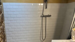 Un baño con ducha, lavamanos y piso estampado.