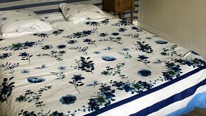 A bed with a floral-patterned bedspread, a bedside table with a lamp, and a wall-mounted mirror. - Guest Room “Île de Bréhat” (Île-de-Bréhat)