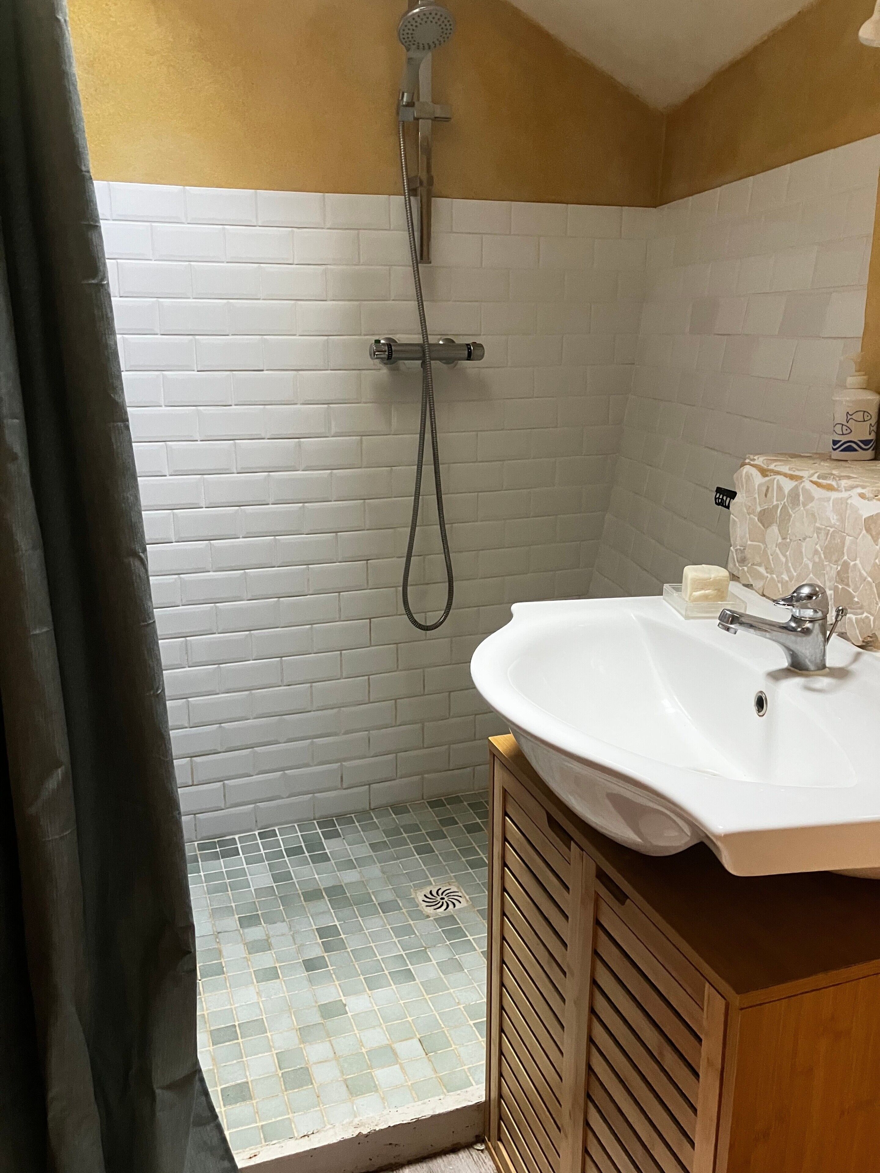 Une salle de bain avec une douche, un lavabo et un sol carrelé.