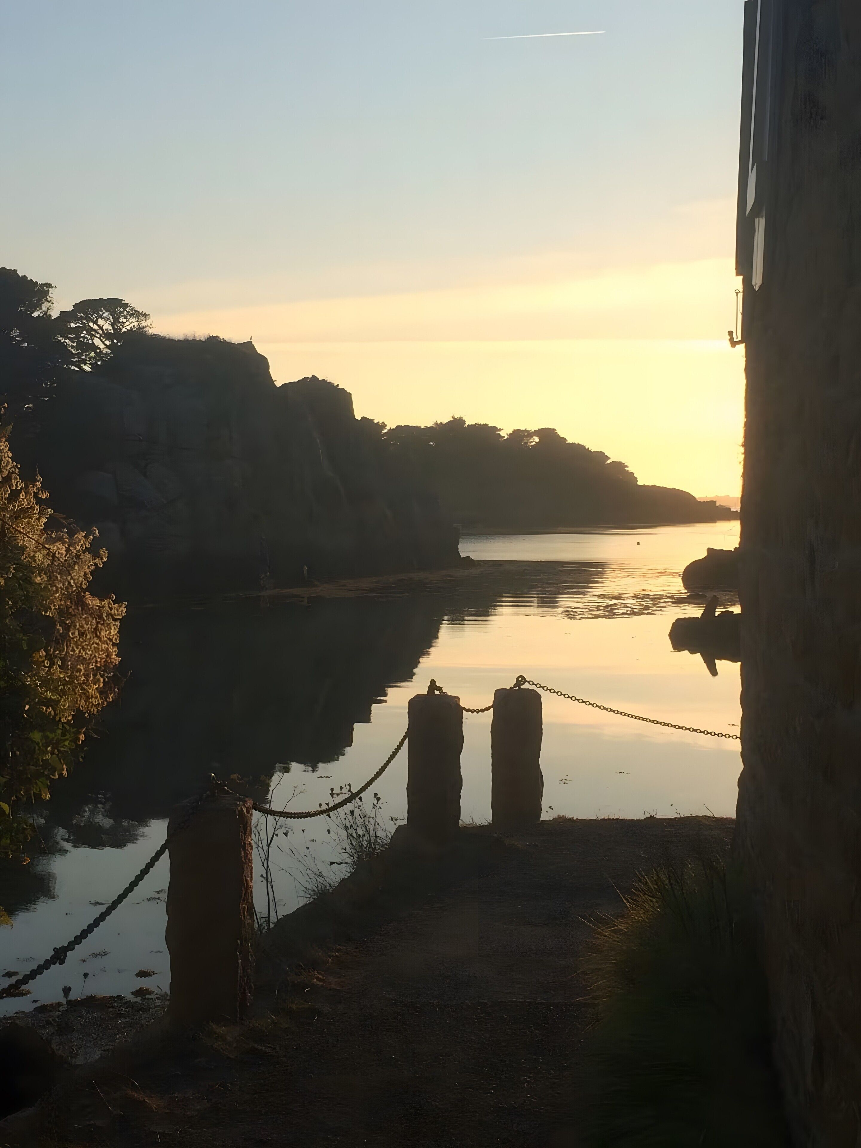 Une rivière paisible, un pont, des falaises rocheuses et une barrière en chaîne.