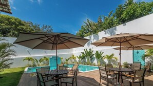 A poolside area with outdoor seating and umbrellas. - Aprts in a Condomin. w/ Pool and Bbc, Imbassai - Foss (Mata de São João)