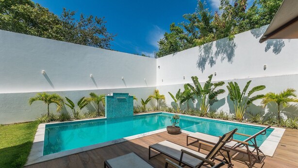 A rectangular swimming pool with a tiled edge, surrounded by a wooden deck and lounge chairs. - Aprts in a Condomin. w/ Pool and Bbc, Imbassai - Foss (Mata de São João)