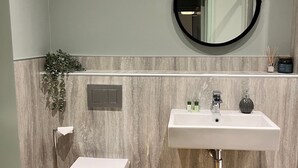 Ein modernes Badezimmer mit Toilette, Waschbecken und Spiegel.
