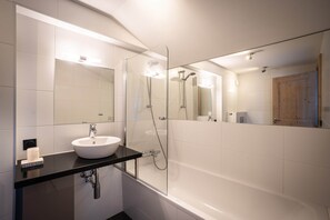Un bagno moderno con lavandino bianco, piano di lavoro nero e zona doccia vetrata.