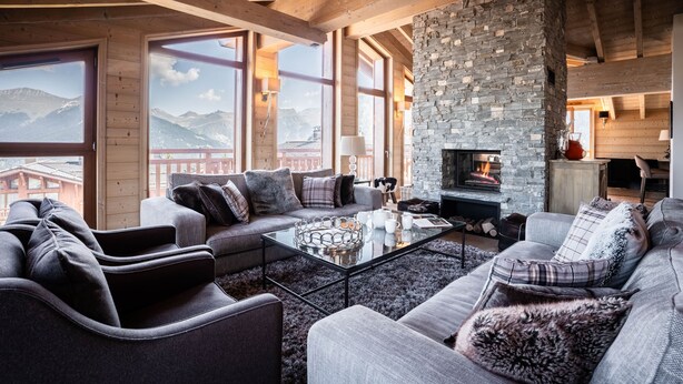 Una sala de estar acogedora con chimenea de piedra, ventanas amplias y vistas a las montañas.