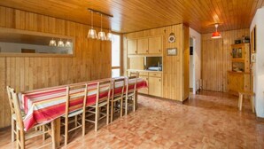 Ein Holzinterieur mit Esstisch und Stühlen, Holzschränken und Pendelleuchten.