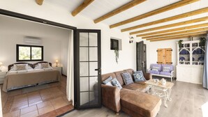 Àmplia zona d'estar amb un sofà, una taula de centre i un llit amb vistes.