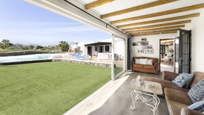 Àmplia zona d'estar amb un gran finestral que dona a una piscina i zona de seients a l'exterior.