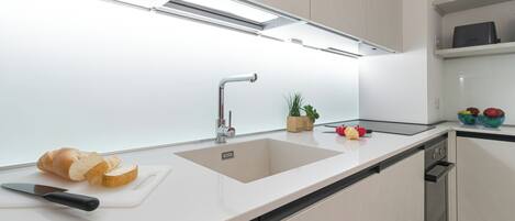 A modern kitchen with a sink, countertop, and a cutting board with bread and a knife.