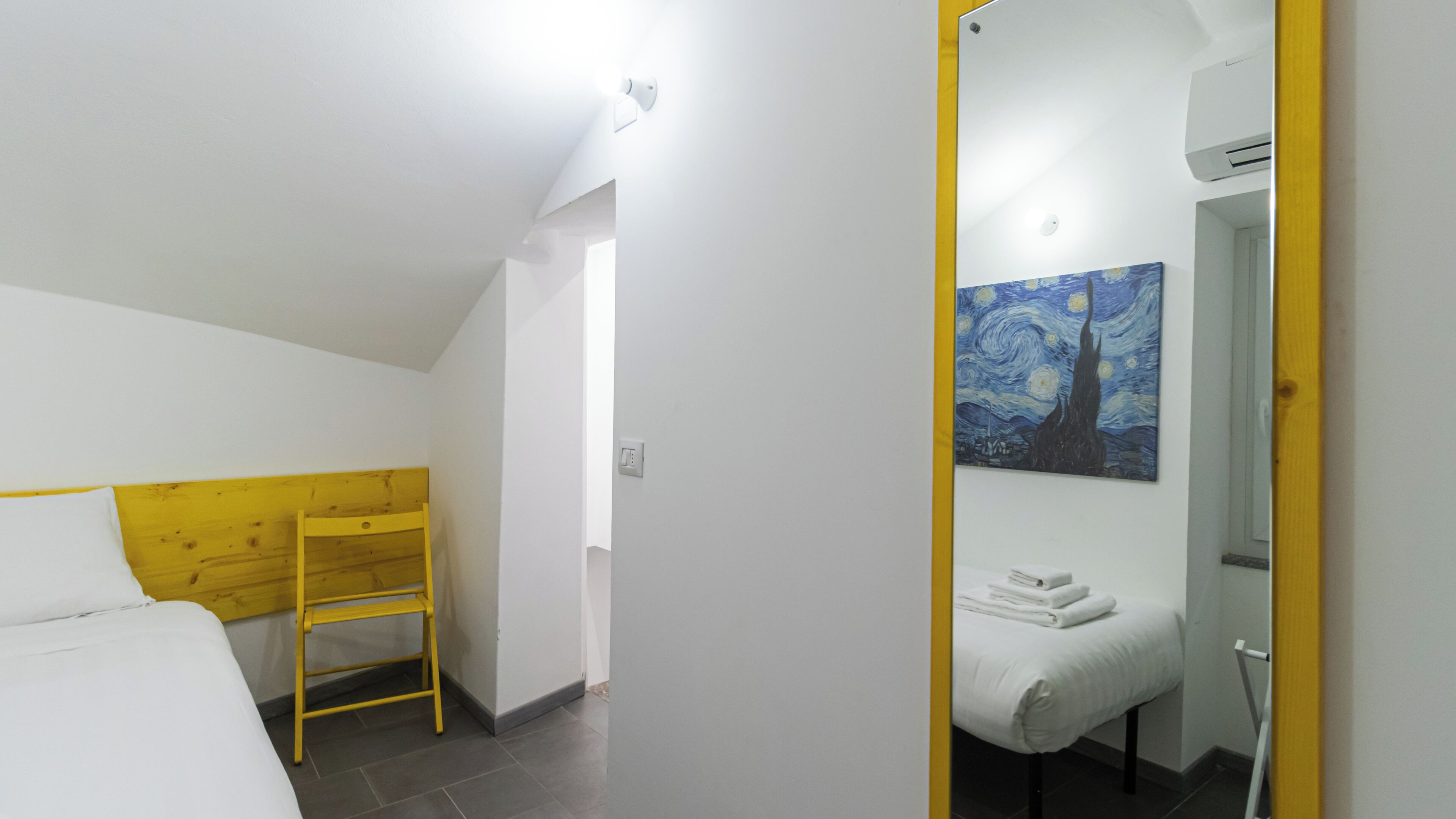 A bedroom with a bunk bed, a painting, and a bathroom with a towel rack.