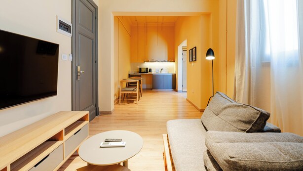 Un salon moderne avec un téléviseur à écran plat, une table basse en bois et un canapé.