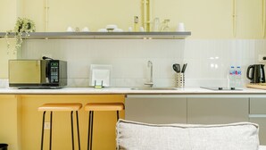 Une cuisine moderne équipée d’un four à micro-ondes, d’une machine à café et de tabourets de bar.