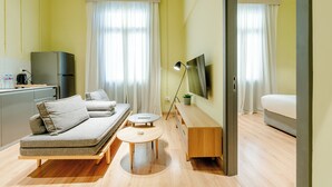 Une chambre d’hôtel moderne équipée d’un canapé, d’une petite table, d’une télévision et d’un lit.