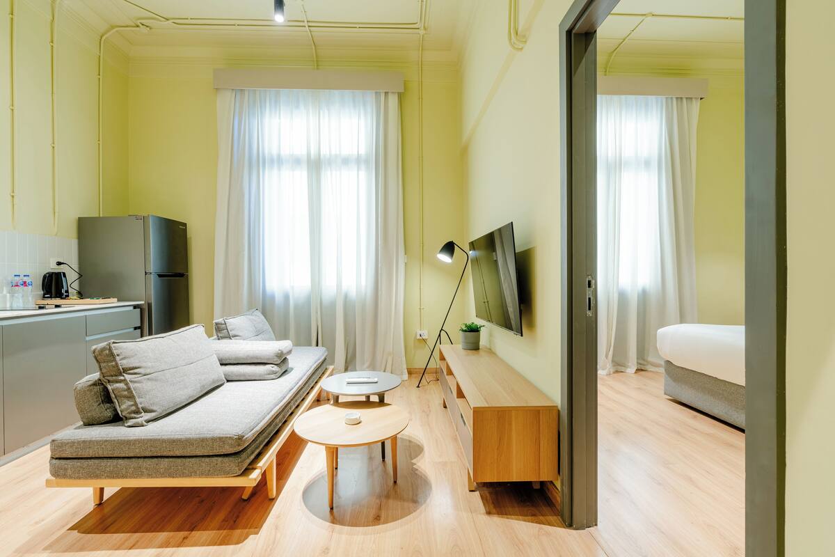 Una habitación de hotel moderna con sofá, una mesita, televisor y cama.