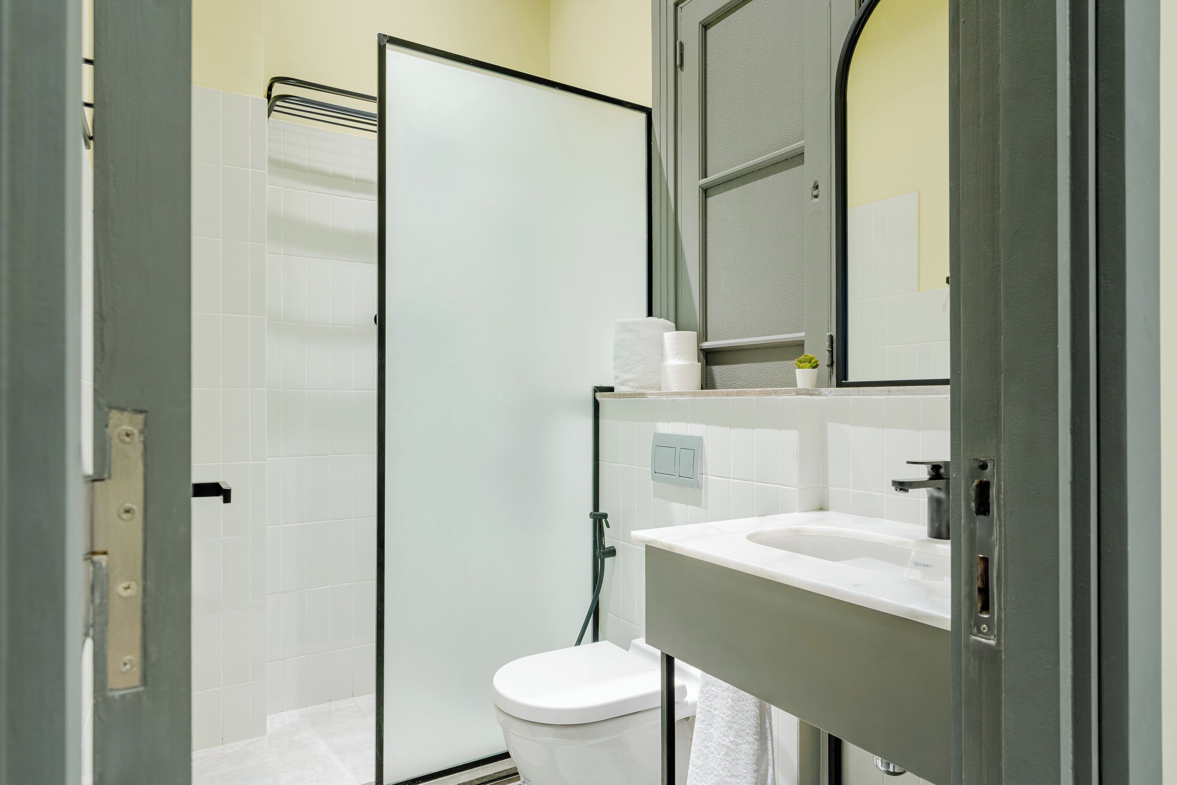 A modern bathroom with a glass shower enclosure, a white toilet, and a sink with a mirror above it.
