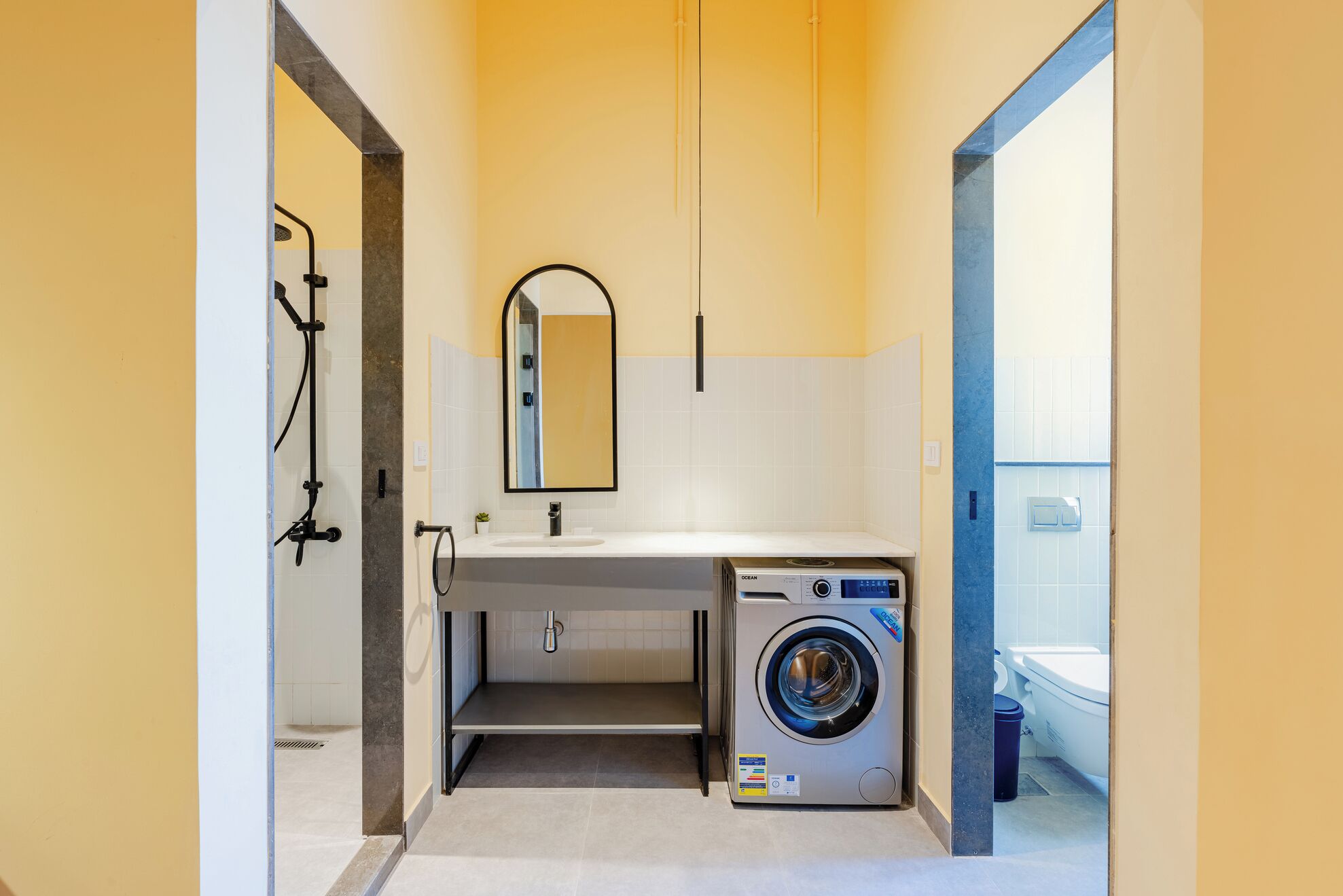 A compact bathroom with a washing machine, a sink, and a toilet.