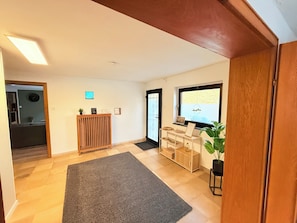 A spacious living area with a wooden floor, a grey rug, a wooden cabinet, and a window with a view. - Cozy vacation apartment in Nideggen-Berg (Nideggen)