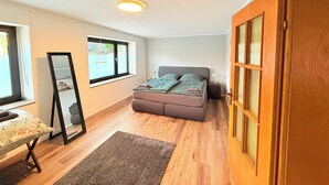 A bedroom with a bed, a bedside table, a mirror, a window, and a door. - Cozy vacation apartment in Nideggen-Berg (Nideggen)