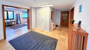 A spacious room with a large window, a door labeled 'Provence,' and a wooden cabinet with a plant on top. - Cozy vacation apartment in Nideggen-Berg (Nideggen)