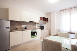 Una cocina moderna con refrigerador, horno y un comedor con mesa y sillas.