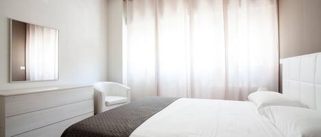 Een moderne hotelkamer met een groot bed, een nachtkastje, een stoel en een kledingkast.