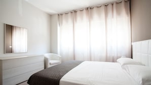 Una habitación de hotel moderna con una cama grande, una mesita de noche, una silla y un armario.